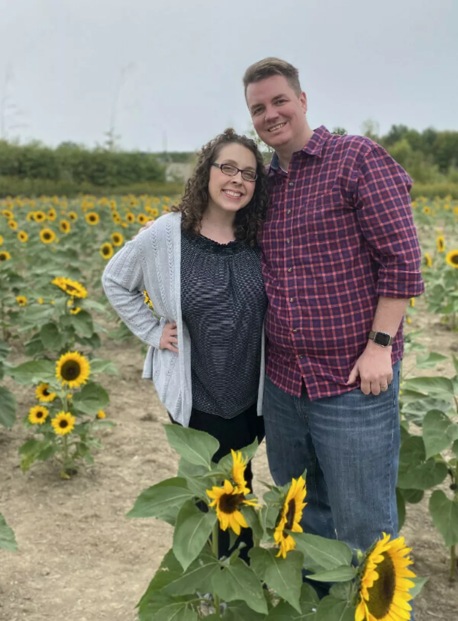 Josh and Natalie Walsh standing in a field of sunflowers